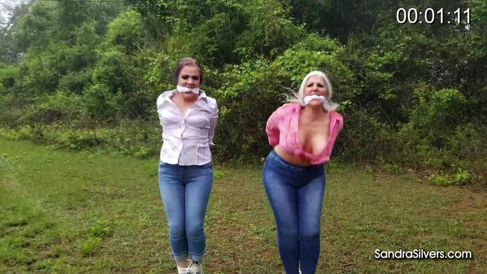 2860 Sandra Silvers and Whitney Morgan Bound and Gagged Denim-clad Damsels Attempt to Hop for Freedom - Outside in the Rain!<br><br>In the cramped outhouse Sandra and Whitney stretched sore, aching muscles as best they could manage in their confines, while both were tied with simple yet effective lengths of rope, wrists tied behind backs and ankles tied together. They were steeling themselves, the moment had come… The shed door bursts open as they make their bid for freedom, wide eyed and immediately wet haired, make up streaming, from the downpour outside! Mouths gagged with knotted cloth, the big breasted pair struggle and bounce, breath heaving their chests as each jump makes them bite onto their gags. Sneakered feet stumble and slip over the rainy field, but the combination of wet grass and hobbling hinders their progress. Hopes of escape are dashed as the dripping damsels realize their holder was just retrieving a van. He bundles them into the back of the vehicle, denim jeans and cotton shirts sopping wet, sorry squeals faintly heard over the relentless storm as they are driven to their secured fate...<br><br><span style='color:#b0b0b0;'>[隐藏文字，购买后可见]</span>