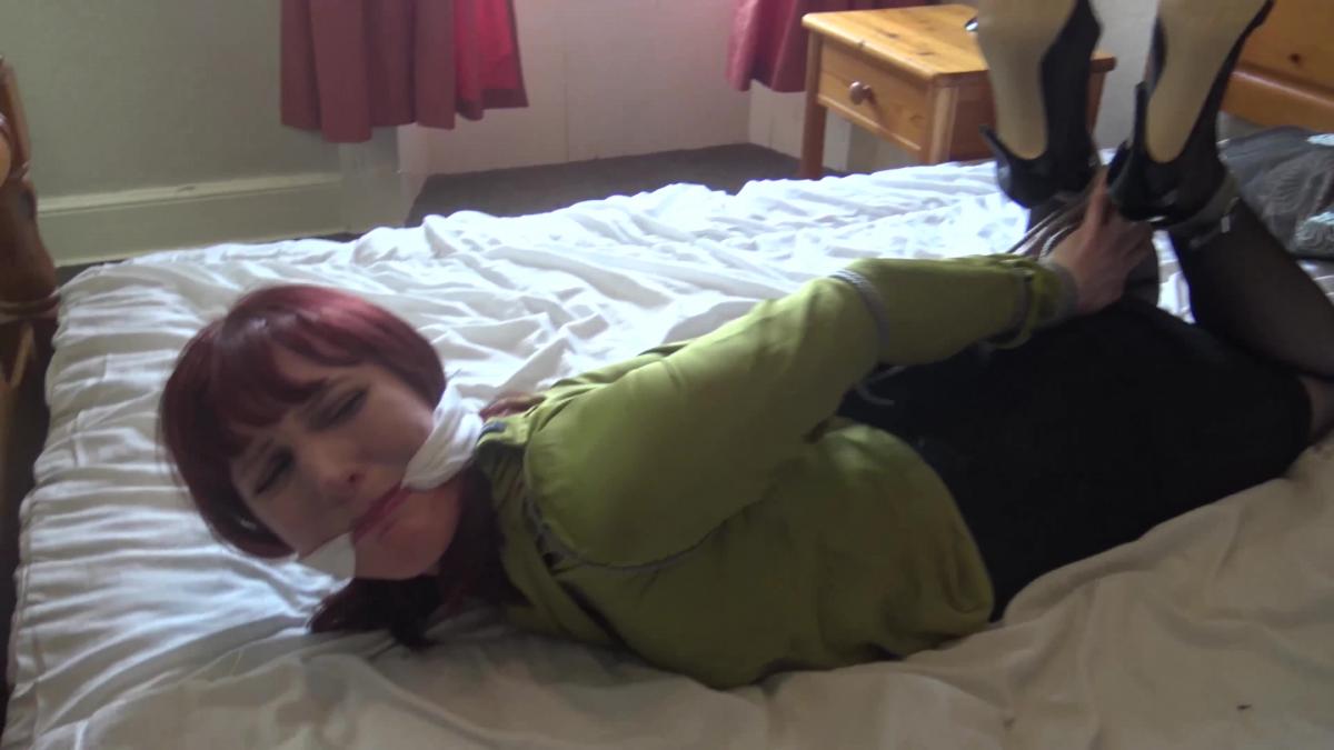 Hogtied Kitty <br><br>Kitty Quinzel is a secretary who has been told to take money to the bank. she had left her office and was making her way there and suddenly a hood was thrown over her head. Someone knew she had the money in her bag and wants it for themselves. so we come and find her Hogtied and gagged on a bed.<br><br>He has fled with the money and will let the police know where she is once he has fled the country with the cash. this guy has tied a rope around the top of her shoulders and tied her arms all the way down to her wrists. the rope is wrapped tightly around the sleeves of her shirt and it's tightly tied around her wrists.<br><br>he has tied her ankles tight and pulled her legs up and hogtied her tightly. she wriggles against the ropes and all she does is raise her skirt exposing her stockings and suspenders she wriggles against the bindings and tugs at the rope with her tied ankles. she has high heels on and tries to unbuckle the strap on her left ankle hoping that she might get her ankles free if she slipped her shoes off. she manages to slip off a shoe but the strap won't open.<br><br>she is just tied up too tight. she can't scream for help as the cleave gag is pulled in between her teeth keeping her quiet. it looks like you are staying here girl.<br>