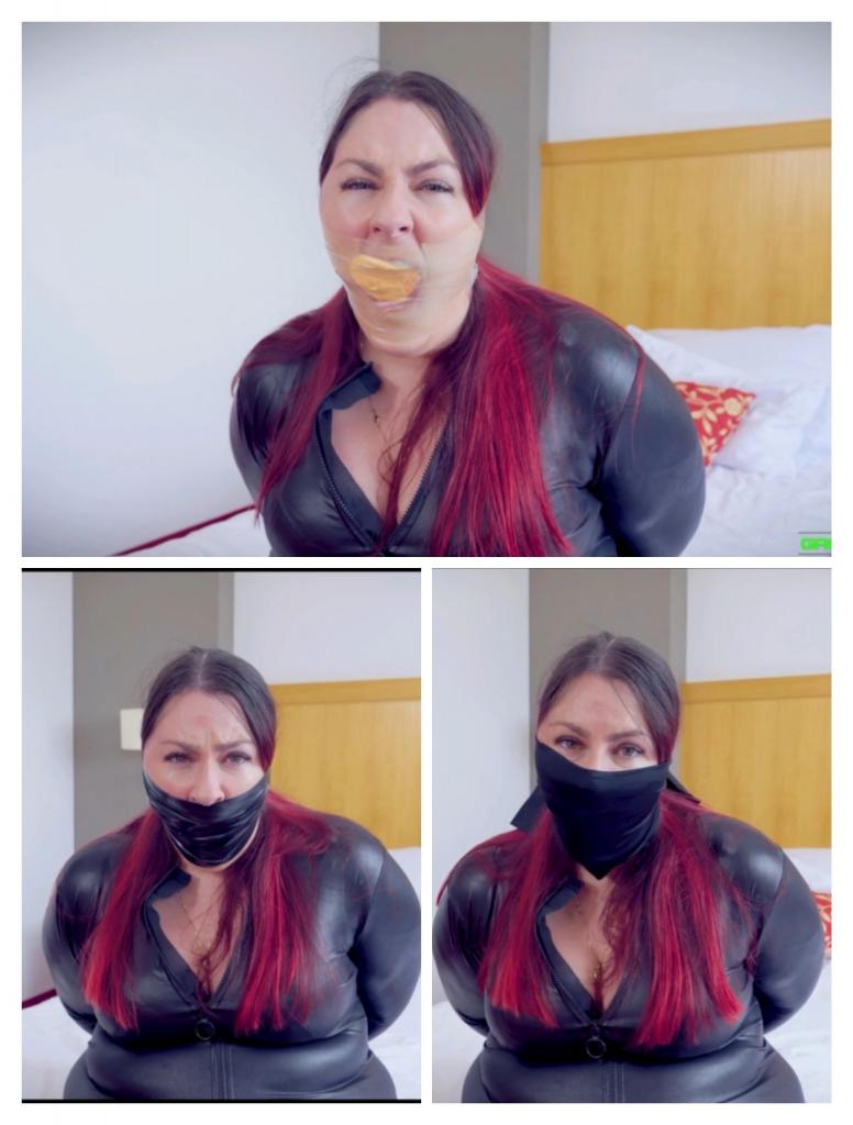Lacey - Catburglar Caught Snooping Lacey is snooping around in a tight catsuit when she finds cuffs and tries them out. HOW is she getting out of these? The owner of the house comes and he tightly puts the mbehind her back. He stuffs her mouth and wraps clear tape around as a wrap gag she is left to struggle and MMMMMPPPHHH. The gag gets and addition a tight black tape wrap gag. Lacey is even more determined to produce sounds through the gag but all that is coming out is muffled gag sounds. The black tape is taken off and there is an OTN placed over the clear wrap gag that is left. She tries to protest but there is only mmmmppphhhing coming out of her mouth. Her gags get removed beffore she is turned over to the police.