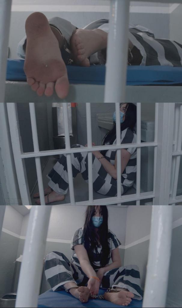 First Time Offender : Jade Pierce's First Time In Prison Part 2 -Masked prison inmate first nig First Time Offender : Jade Pierce's First Time In Prison Part 2 -Masked prison inmate first night locked up in a prison cell innocent girl next door self surrenders for 3 year prison sentence, barefoot handcuffed and shackled in uniform 杰德初次入狱经历（第二部分）：<br><br>杰德是个紧张但基本顺从的新犯，今天早上主动投案，开始为期三年的州立监狱刑期。她交出了所有衣物和个人物品，并领到了一套新的囚服：经典的黑白条纹囚服，以及一个橙色的塑料腕带，上面印着她的照片、编号和其他身份信息，方便狱警快速识别。仅此而已。<br><br>她被戴上手铐和脚镣，押送到牢房。狱警打开牢房门时，她面朝墙壁。她向内窥视着自己的新家，第一次看到不锈钢马桶和洗手池，它们就安装在离水泥床铺一英尺远的地方。牢房很小，阴冷，灰蒙蒙的，除了窗户之外，没有任何装饰。杰德之前想象的监狱生活，现在才真正面对。她叹了口气，看着门为她打开。<br><br>杰德被锁进牢房后，手铐被移到前面，狱警让她先待一会儿。<br><br>观察这位女囚最初被关起来的反应很有意思。门关上了，狱警走开了，杰德几乎一动不动地站在那里。她盯着面前的床铺，焦虑地焦躁不安，抓挠着头发，然后无力地垂下双臂。杰德最终背靠着床尾的墙壁坐了下来，紧紧地贴着牢房的门。她偶尔会回头看看厕所，但实际上她几乎没怎么踏进牢房。她尽可能地靠近牢房门，只是偶尔从肩后瞥一眼新房间的布置和设施。这或许可以理解为杰德仍在试图拒绝或否认自己真的被关进了这间牢房，否认这里就是她的家。这突如其来的现实让她难以接受。<br><br>狱警拖着她的床走了进来，杰德从门口站了起来。蓝色的床垫和枕头被扔到地上，杰德双手被铐着举过头顶，站在牢房后方，等着狱警把床铺放好。狱警递给她一盒洗漱用品和其他一些生活必需品。狱警背诵着一长串关于这个小型塑料个人物品盒的规定，对她滔滔不绝地讲解着。他离开牢房，把她重新锁上，然后让她举起双手，解开手铐。她的手腕被解开，这样她就可以在牢房里稍微舒服些了。不过，用“舒服”这个词来形容她现在的处境或许并不恰当。<br><br>杰德检查了盒子里的东西，但她似乎不太高兴，因为她现在唯一的财产只有一块肥皂、一把牙刷、一把梳子、一支笔和几张纸。除了做点什么之外，她还能做什么呢？只能望着墙壁，透过铁栏杆望着别的墙壁，或者低头看着自己被镣铐锁住的双脚和身上那件让她动弹不得的囚服。三年在人生的长河中并不算长，但在这里，时间却仿佛被无限拉长。<br><br>在接下来的视频中，杰德继续沉浸在难以置信和恐惧之中。她拉扯着镣铐，脸朝下趴在床上，在牢房里踱来踱去，坐在马桶上，徒劳地用笔抠着镣铐，跪在地上，脸埋在枕头里，捂着肚子，一阵阵恶心和焦虑袭来，这是她适应囚犯生活后产生的反应。<br><br>她似乎仍然坚称自己无罪，但无论如何，审判早已结束。这就是判决，她的惩罚不容商榷。如果杰德真的认为法庭判错了，她可以在狱中提出上诉；或者她也可以开始承担责任，争取提前释放。但今天，这些都无关紧要。更普遍的情况是，她所在监区的狱警根本不在乎这些，所以此刻，她为自己辩解的声音只能被牢房的墙壁听到。<br><br>狱警告诉囚犯们，灯很快就要熄灭了，所有人都必须回到自己的床上。杰德躺下，盯着天花板，牢房里的灯渐渐熄灭。明天，她将在这间牢房里醒来，穿着这身衣服，仍然戴着镣铐，被锁着。早上她要起来点名，然后就只能虚度光阴，直到又一天刑期结束。杰德抬头望着牢房的天花板，思索着未来的处境，以及还有多少天要熬过去。看来，这第一个夜晚，她恐怕是没法好好休息了。Part 2 of Jade's first time being locked up:<br><br>Jade is a nervous and mostly compliant new convict who self surrendered this morning to begin a 3 year state prison sentence. She has turned over all her clothes and possessions, and been given her new clothing as an inmate: classic black and white striped scrubs, and a plastic orange wristband displaying a mugshot, number, and other identifying information for quick reference by her jailors. Nothing else.<br><br>Handcuffed and shackled she is walked to her cell. She faces the wall while the CO unlocks and opens the cell door. She peers in at her new home, for the first time seeing the stainless steel toilet and sink installed a foot away from the concrete bunk that makes the cell's bed. It is very small, cold, grey, and otherwise featureless little cell, with no windows. Whatever Jade had pictured being in prison was going to be like, now she is looking right at it for the first time. She sighs looking in as the door is opened for her.<br><br>After Jade is locked in, her handcuffs are moved to the front and she is told to settle in for a bit.<br><br>It is interesting to see how the inmate handles her first moments locked up. The door is shut, the guard walks away, and Jade barely moves from her spot. She stares a the bunk in front of her and anxiously seethes, pulls at her hair, then slumps her arms hopelessly. Jade eventually sits down with her back against the wall of the foot of the bed and stays pressed to the door of her cell. She looks back at the toilet occasionally but has barely set foot into the cell. She's staying as close to the door as she can, and only glimpsing at her new room's features and fixtures from over her shoulder. This could be viewed perhaps as Jade still attempting to refuse or emotionally deny to herself that she is actually locked in this cell, and that this is home now. It's a difficult pill to suddenly be swallowing.<br><br>Jade stands up from the door when one of the guards arrives dragging in her bed. The blue mattress and pillow are tossed down, and Jade stands at the back of the cell with her cuffed hands up on her head while the bedding is put in her cell. A box of toiletries and some other basics are given to her. The CO speaks at her with a memorized laundry list of rules regarding this small plastic personal property box. He leaves the cell, locks her back in, and then has her present her hands to have the cuffs taken off. Her wrists are freed so she can start getting more comfortable in her cell. Comfort perhaps not being the right word to use there.<br><br>Jade inspects the things in her box, but doesn't seem too happy to have her only possessions now be a bar of soap, a toothbrush, a comb, and pen, and a few pieces of paper. Beyond doing something with these things, her options will be to look at the walls, look out the bars at some other walls, or stare down at her own shackled feet and the prison uniform she is stuck wearing. 3 Years is really not that long of a time in the scale of a persons life, but time here will feel stretched beyond belief.<br><br>For the rest of the video Jade continues a cycle of disbelief and horror at her situation. She tugs at her chains, lays face down on her bunk, walks around the cell, sits on her toilet, try's hopelessly picking at her shackles with a pen, kneels over on her knees with her face in the pillow clutching her stomach as the wash of retching anxiety that accompanies adjusting to now having to live as a prisoner takes it's hold.<br><br>She seems to still maintain that she is innocent, but either way the court case is now long over. This is the verdict and her punishment is non-negotiable. Jade may file an appeal from within prison if she really believes the court got it wrong, or she can start taking responsibility and trying to secure an earlier release, but today it doesn't really matter. More generally the CO's in the unit she is assigned don't care about any of this so the pleading of her innocence is only heard by the walls of her cell at this point.<br><br>The inmates are told the lights are going out soon, and all inmates need to be on their bunks. Jade lays down and stares at the ceiling as the lights in her cell go out. Tomorrow she will be waking up in this cell, wearing these clothes, still shackled and locked up. She will get up for a headcount in the morning and then spend the day passing time until yet another one is marked off her sentence. Jade looks up at the ceiling of her cell contemplating this future and how much is now left to go. It seems unlikely she will be getting much rest on this first night.