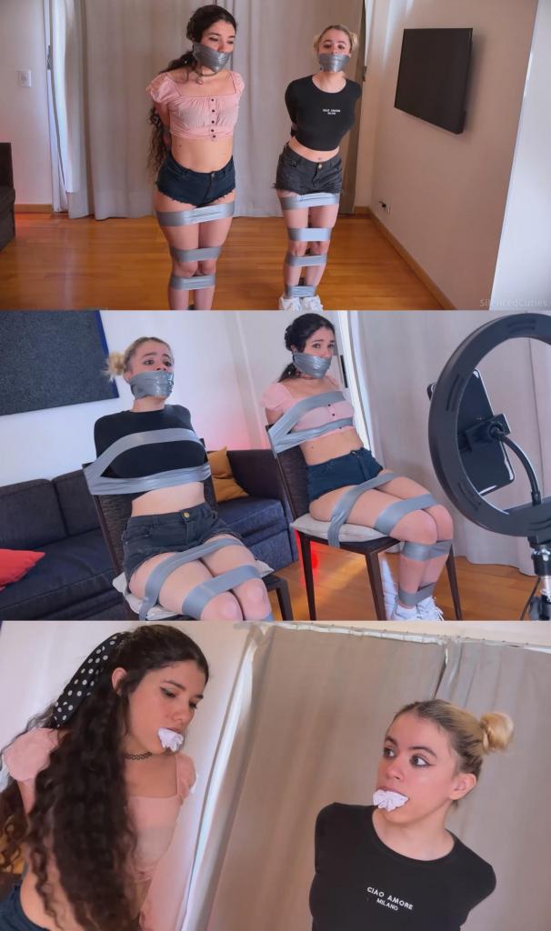 Summoned Into Bondage?! Nani and Addy Get TIGHTLY TAPED After Their Candle Ritual! - mouth stuffed,  Summoned Into Bondage?! Nani and Addy Get TIGHTLY TAPED After Their Candle Ritual! - mouth stuffed, tapegagged, magic bondage, struggling 娜妮和艾迪进行仪式时，万万没想到自己会被召唤出来的实体用胶带紧紧捆绑，嘴巴被布塞得满满的，还被一层又一层胶带严严实实地封住了！<br><br>娜妮和艾迪正讨论着如何召唤实体，艾迪突然犹豫起来，问这是否真的存在。娜妮安慰她说别这样，如果成功召唤出来，她们就可以许愿，而且会很有趣。<br><br>她们在客厅中央摆放了几根蜡烛，用火柴点燃。她们手牵着手，按照召唤仪式进行，祈求召唤成功。<br><br>她们吹灭蜡烛，笑着互相好奇地看着对方。过了一会儿，她们意识到什么也没发生，可能是自己哪里做错了。娜妮提议再试一次，但艾迪说够了，这只是常识而已。<br><br>突然，她们听到胶带的声音从某个地方传来。娜妮和艾迪感觉自己的身体像模特一样被向上拉起，她们双手被一股无形的力量压在背后，不知发生了什么。<br><br>然后灯灭了。当灯再次亮起时……她们俩都被胶带完全缠住了！<br><br>娜妮和艾迪开始呻吟，不知道发生了什么，她们左右摇晃着身体，拼命挣扎着想要摆脱紧紧缠住她们胳膊和腿的胶带。这胶带是从哪儿来的？缠得也太紧了吧！<br><br>艾迪责备娜妮，说她的计划失败了。她们开始四处乱跳，寻找可以解开绳子的东西。她们一路跳到卧室，门突然砰的一声关上了。她们仍然被紧紧地绑着，双腿也被胶带缠在一起。她们不知道那个东西是想报复她们，还是想实现她们的愿望。她们跳回客厅，寻找剪刀，这时她们看到了娜妮的手机。她走近手机准备拨号，灯又灭了。当她们再次醒来时，她们可爱的小嘴巴被布塞住了！嗯嗯嗯嗯！<br><br>灯再次熄灭，现在她们的头被紧紧地缠上了一条灰色的PVC胶带，嘴也被堵住了。娜妮和艾迪开始呻吟，肩膀左右摇晃，一边发出“嗯嗯嗯嗯！”的疑问声。她们摇着头，胸部也随之晃动，然后又蹦蹦跳跳地往卧室走去。<br><br>她们只能用眼睛扫视房间，身体其他部位都动弹不得。一无所获后，她们决定跳回客厅。嗯嗯嗯嗯！<br><br>娜妮在沙发里翻找了一番，摇了摇头。然后她们跳向门口，拼命地想要挣脱胶带的束缚，突然……那个东西出现了！她们疯狂地跳向窗户，但还是被抓住了，然后她们全部消失了。<br><br>娜妮和艾迪再次出现时，被绑在椅子上，只能发出“呜呜呜”的声音。她们扭动着身体，呜咽着，嘴唇被胶带封住，双手被反绑在椅背上。她们真的以为自己能逃脱吗？可爱的艾迪穿着白色运动鞋，小脚丫扭来扭去，娜妮则扭动着双手，手腕却动弹不得。<br><br>当她们意识到这一点时，她们正被手机实时拍摄！她们看到自己被绑在椅子上，完全无助。她们看起来真是太可爱了！<br><br>她们能从那个“恶灵”手中逃脱吗？还是它会满足她们的愿望，让她们永远被束缚在成功之中？When Nani and Addy performed the ritual, they never imagined that they would magically end up bound with tape, their mouths completely stuffed with cloth and sealed with tight turns and turns of tape by a summoned entity!<br><br>Nani and Addy are talking about summoning an entity when Addy hesitates, asking if it's real. Nani tells her not to be like that, if they manage to summon it, they'll make a wish and it’ll be fun.<br><br>They arrange some candles in a circle in the middle of the living room, lighting each one with a match. They hold hands, follow the summoning ritual, and ask to be bound to success.<br><br>They blow out the candles and laugh, looking at each other with curiosity. After a while, they realize nothing is happening and that they might have done something wrong. Nani suggests trying again, but Addy says it's enough, it's just common sense.<br><br>Suddenly, they hear the sound of tape coming from somewhere. Nani and Addy feel their bodies being yanked upward like mannequins, wondering what's happening as their hands are pressed together behind their backs by an invisible pressure.<br><br>Then the lights go out. When they come back on… both of them are fully taped up!<br><br>Nani and Addy start moaning, wondering what’s going on, shaking their bodies from side to side and pulling against the tight tape around their legs and arms. Where did it come from? Those tapes are so tight!<br><br>Addy scolds Nani, saying her idea didn’t work out. They start hopping around looking for something to untie themselves. They hop all the way to the bedroom when the door suddenly slams shut. They’re still tightly bound, legs taped together. They wonder if the entity wants revenge or if it wants to grant their wish. They hop back to the living room, searching for scissors, when they spot Nani’s phone. She moves closer to dial a number when the lights go out again. When they come back on, their cute little mouths are stuffed with cloth! MMPPPPHHH!!<br><br>The lights go out once more, and now they’re gagged with a tight wraparound of gray PVC tape around their heads. Nani and Addy start moaning, shaking their shoulders from side to side, exchanging doubts with “mmpppphhhh!” and “mpphhhh!” They shake their heads, making their breasts bounce as they take little hops back toward the bedroom again.<br><br>They scan the room with only their eyes, unable to move anything else. Finding nothing, they decide to hop back to the living room. MMPPPHH!<br><br>Nani rummages through the sofa and shakes her head. Then they hop toward the door, their bodies desperately trying to escape the tape, when suddenly… the entity appears! They hop frantically toward the window, but it catches them and they all disappear.<br><br>Nani and Addy reappear tied to a chair, only able to say “MMPPPHHH!!” They squirm from side to side, whimpering with their lips sealed by the tape and their arms behind the chair back. Did they really think they could escape? Sweet Addy wiggles her little feet in white sneakers while Nani twists her hands, unable to move her wrists.<br><br>When they realize it, they’re being filmed live on a phone! They can see themselves tied up and taped to the chair, completely helpless. They look so adorable!<br><br>Will they manage to escape from the entity, or will it grant their wish to be bound to success forever?